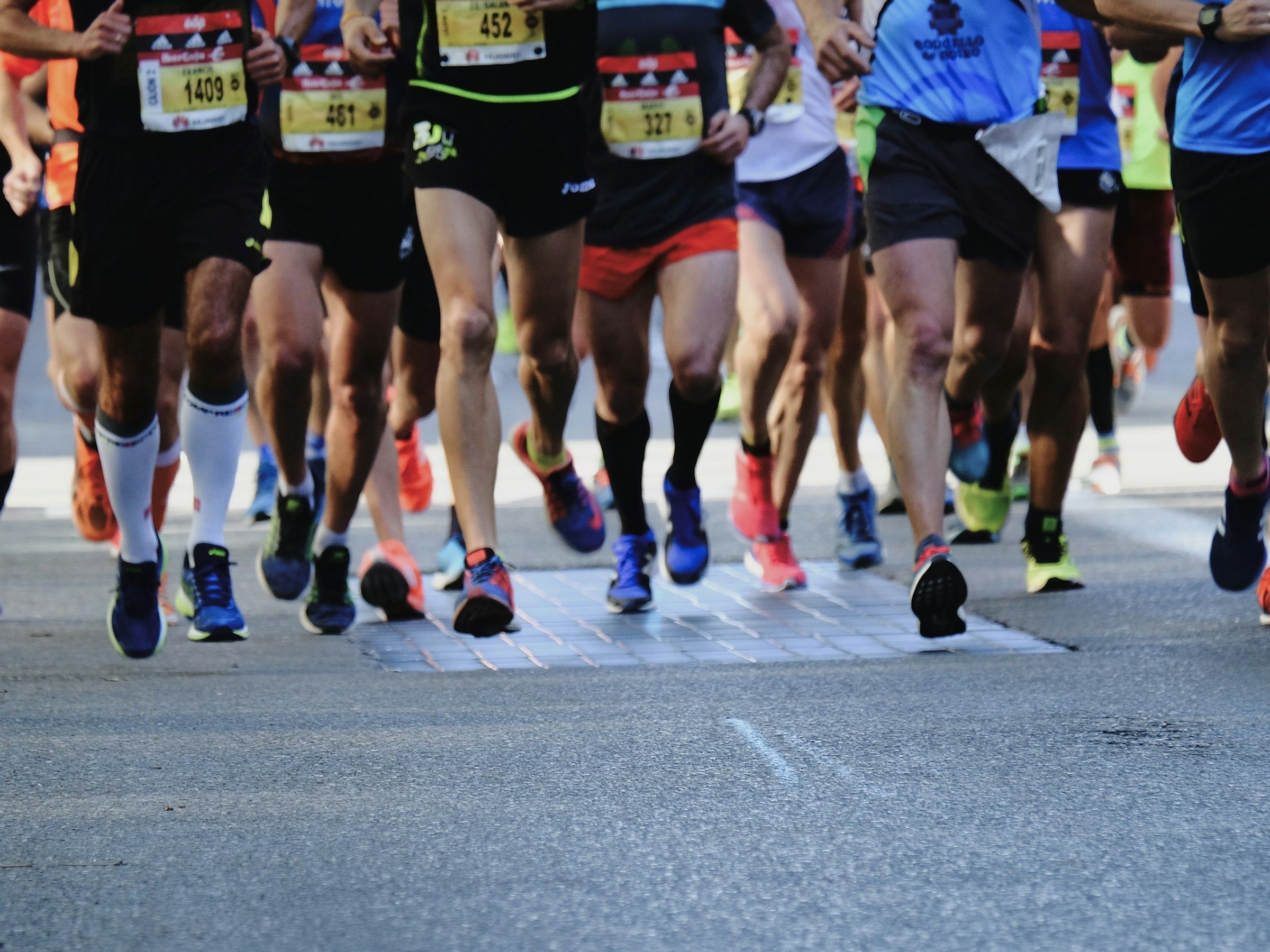 Runners' legs and race bibs at the start of a road race