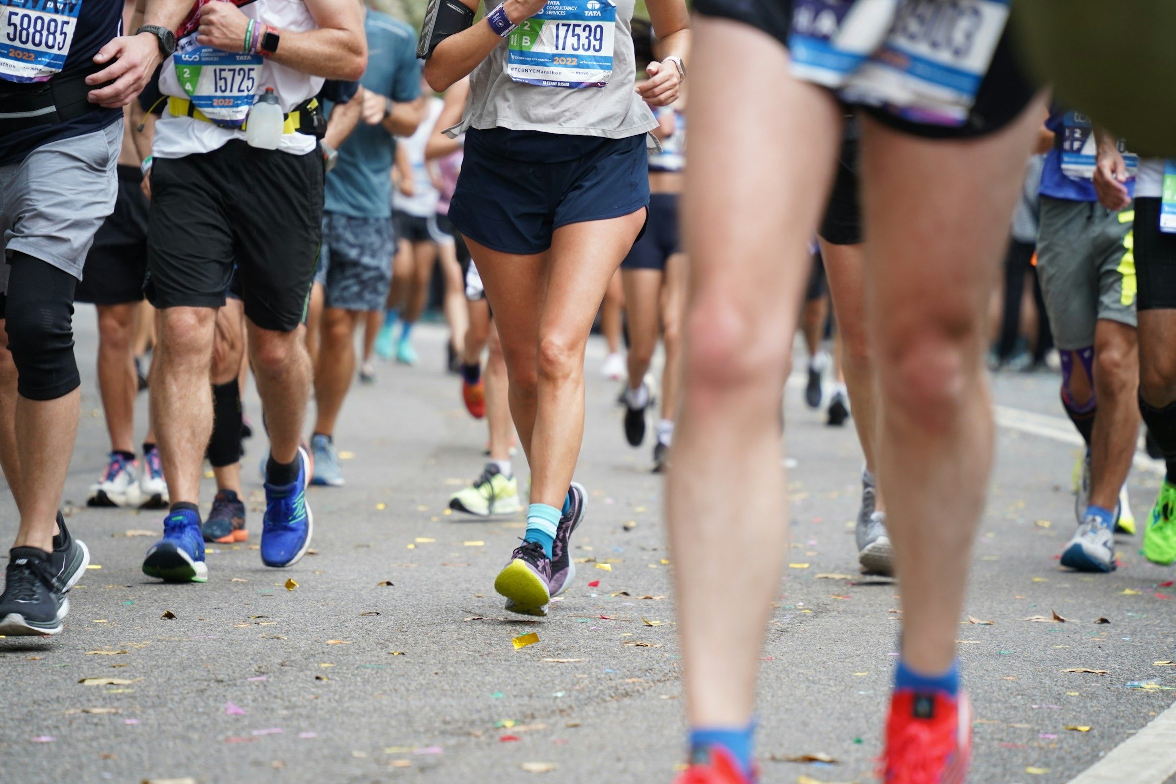 Close view of runners' legs and race bibs on a road