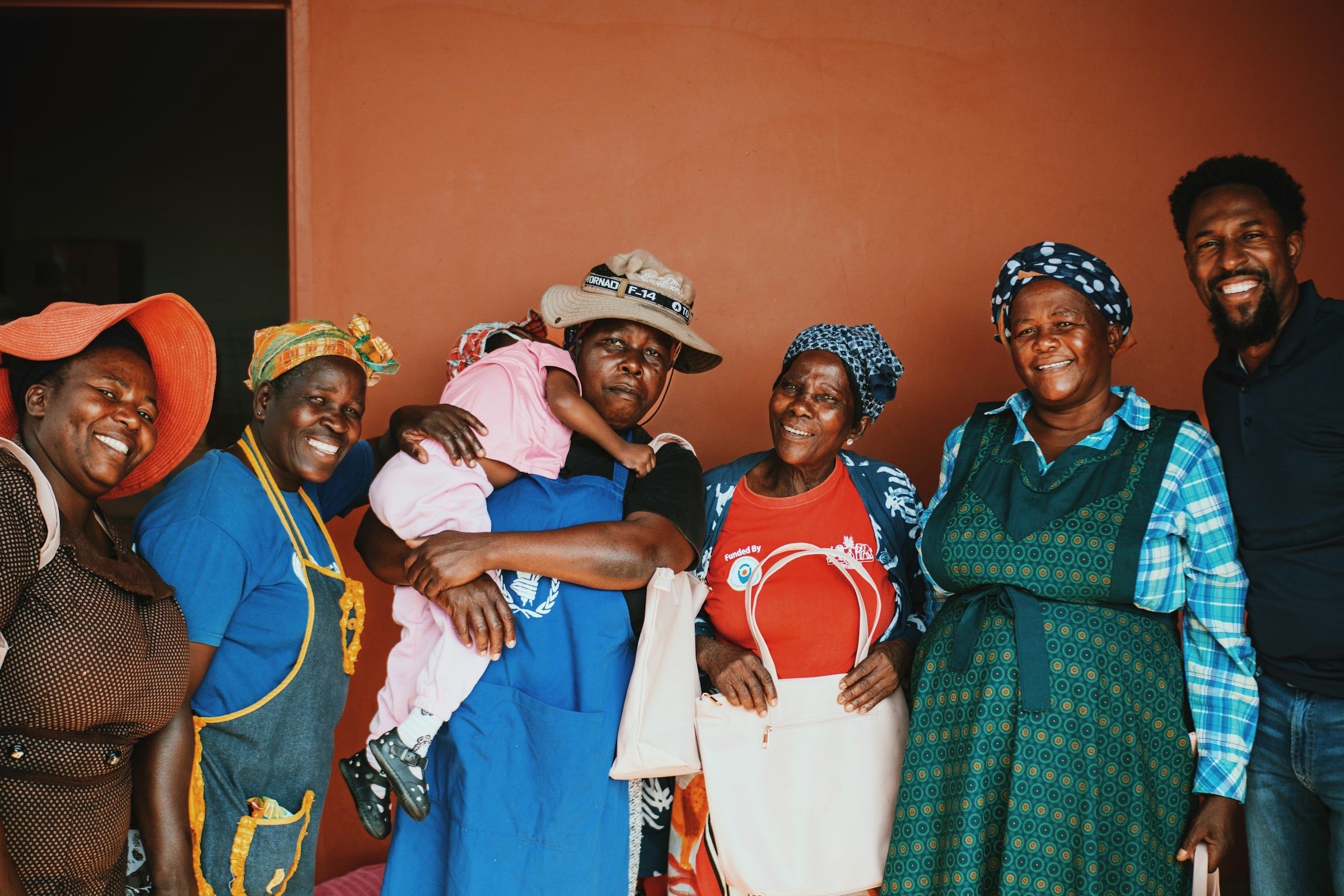 Group of smiling women and a man laughing together in a warm-lit room