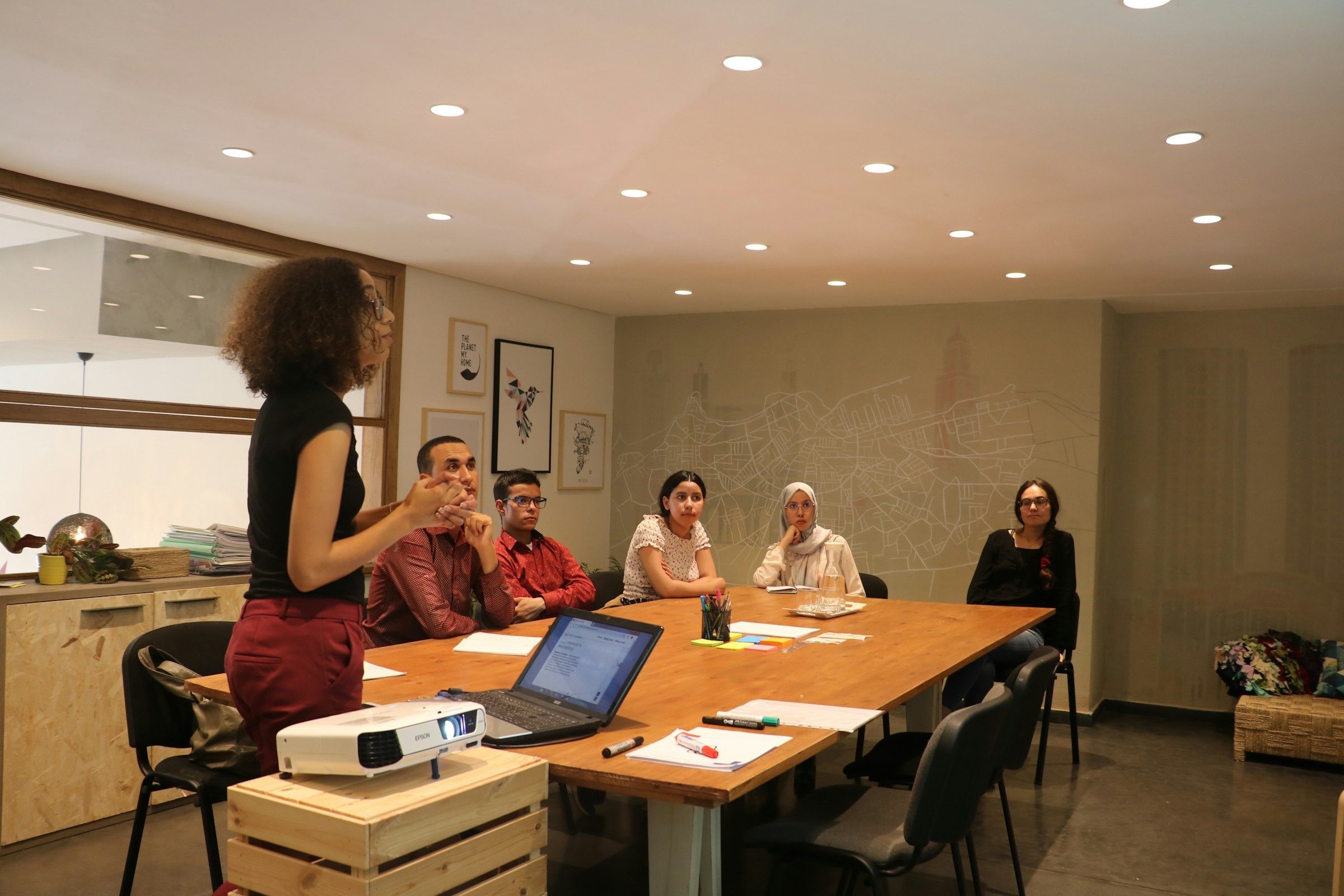 Facilitator standing and speaking to a group around a meeting table