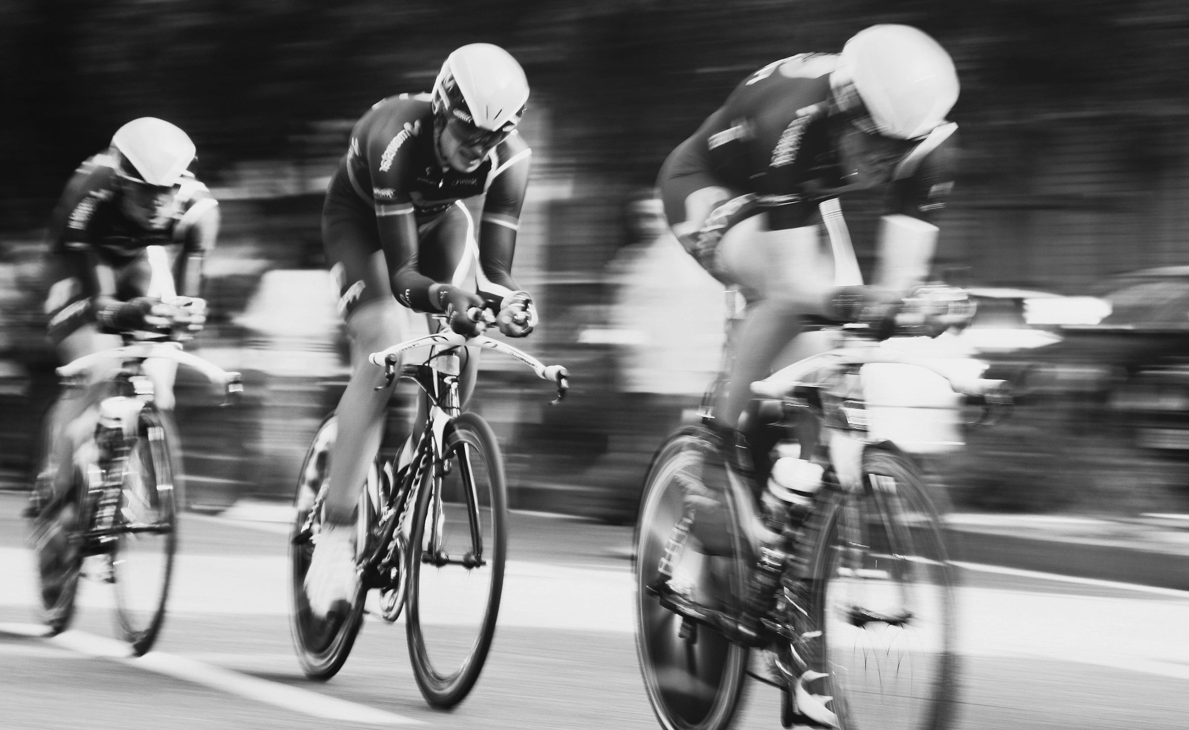 Black and white motion shot of three road cyclists racing