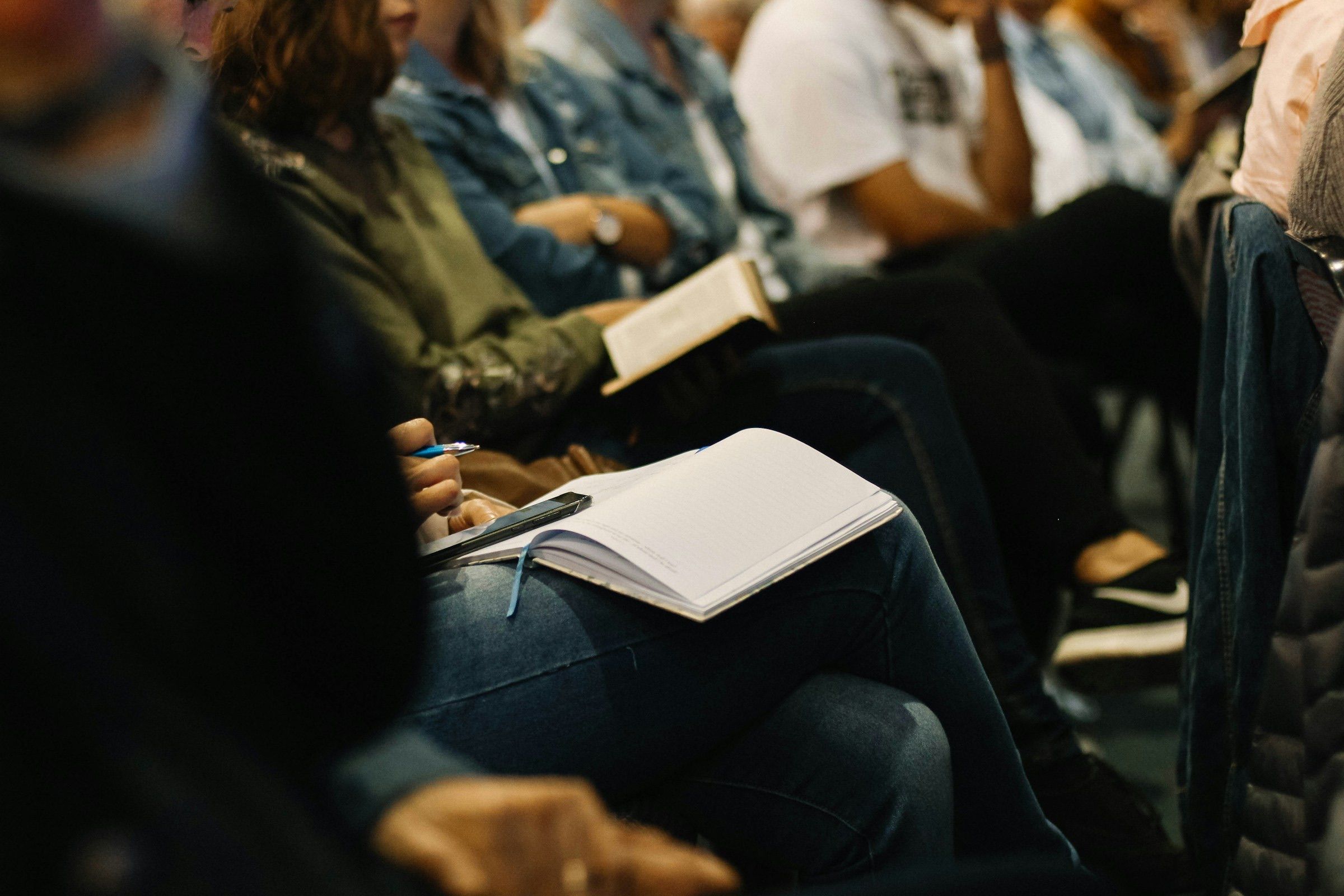 Attendees taking notes in notebooks during a session